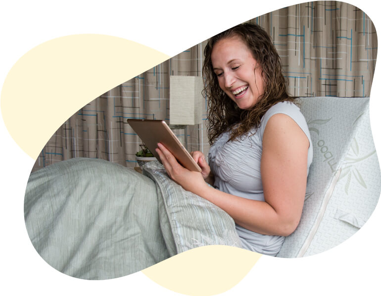 Woman resting her back on the Body Buddy while she reads.